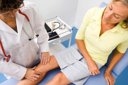 врач осматривает колено пациента
